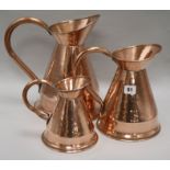 A set of three graduated copper jugs