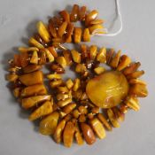 A single strand jagged amber necklace and an amber brooch, gross weight 104 grams, necklace 86cm.