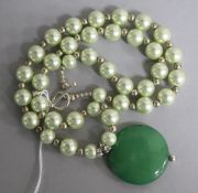 A jadeite disc pendant on a simulated pearl necklace, pendant 39mm.
