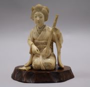 A Japanese carved ivory kneeling woman with musical instrument