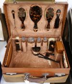 A tan leather travel case, fitted with tortoiseshell and silver brushes and bottles.