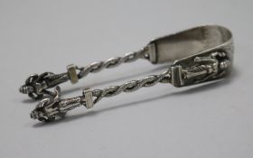 A pair of Indian white metal sugar tongs with figural terminals, 10.8cm.