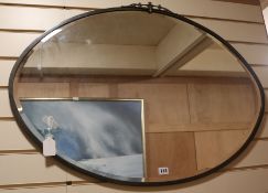An oval brass-framed bevelled wall mirror, W.93cm