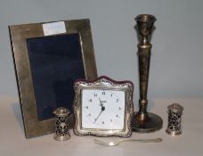 A modern silver mounted photograph frame, a silver mounted timepiece, two peppers and a candlestick,