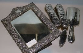 An Edwardian repousse silver mounted photograph frame, Birmingham, 1907, two brushes, a mirror and a