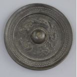 A small Chinese bronze circular mirror, Tang dynasty, 7th-9th century A.D., cast in relief with