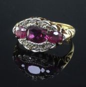 An early 20th century 18ct gold, ruby and diamond oval cluster ring, set with three rubies and