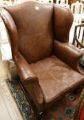 A George III style mahogany wingback armchair re-upholstered in brown leather