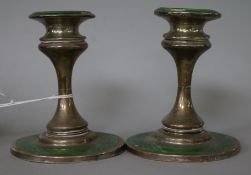 A pair of George V silver and green enamel dwarf candlesticks.