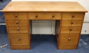 A Gordon Russell oak nine drawer desk W.130cm