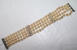 A triple strand cultured pearl bracelet with diamond set white metal clasp and spacers, 19cm.