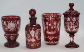 Four items of Bohemian ruby flashed glass, including a panel-cut beaker engraved with decorative