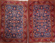 A pair of Persian red and blue ground rugs, with foliate scroll decoration and three row border, 6ft