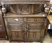A reproduction carved and panelled oak court cupboard