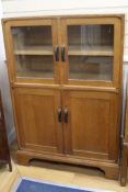 A Gordon Russell oak cupboard, fitted with a pair of glazed doors over panelled doors W95.5cm