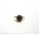 A 9 CARAT GOLD BLUE TOPAZ AND DIAMOND CLUSTER RING the oval cut stone enclosed by twenty single