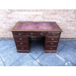 AN EDWARDIAN TWIN PEDESTAL WRITING DESK with red gilt tooled leather top, stamped 'Jas SHOOLBRED'