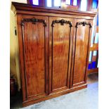 A VICTORIAN MAHOGANY COMPACTUM the three doors carved with fruit and foliage in relief, and