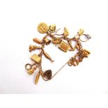 A 9 CARAT GOLD CURB LINK BRACELET with twenty one charms attached, 26g gross