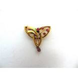 AN ENAMEL AND RUBY BROOCH tagged '15ct', circa 1900, showing Art Nouveau influence, 2.8cm across,