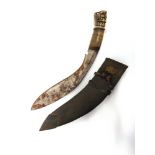 A NEPALESE KUKRI the 29cm typically curved blade with a carved horn grip and lion head pommel, in