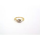 A TWO STONE DIAMOND CROSS OVER RING indistinctly marked, the brilliant cuts totalling