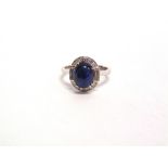 A SAPPHIRE AND DIAMOND 18 CARAT WHITE GOLD RING the oval cabochon, 9mm by 7mm by 4.4mm deep, with