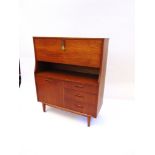 A G-PLAN STYLE TEAK BUREAU drop-down section with fitted interior above three drawers and cupboard