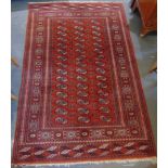 A RED GROUND RUG the central field with three rows of guls within decorative border, 125cm x 190cm