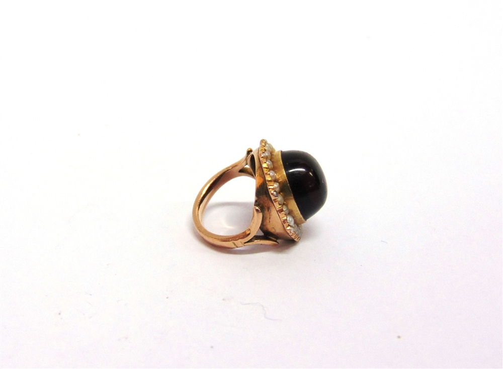 A CABOCHON GARNET RING stamped '9ct', enclosed by a seed pearl border, finger size F, 5.5g gross - Image 2 of 2