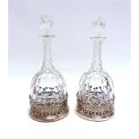 A PAIR OF CUT GLASS DECANTER AND STOPPERS in Old Sheffield Plate coasters, 33cm high overall