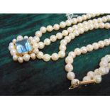 A THREE ROW UNIFORM CULTURED PEARL NECKLACE to an aquamarine and cultured pearl clasp, the 51/51/