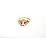 A 9 CARAT GOLD KUNZITE RING the oval cut stone, 9.7 by 7.7 by 5.4mm deep, with a trio of single cuts