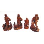 A GROUP OF CARVED HARDWOOD FIGURES OF PEASANTS two feeding chickens, one holding a fish, and another