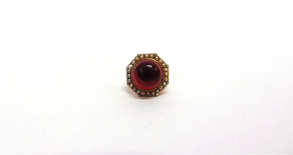 A CABOCHON GARNET RING stamped '9ct', enclosed by a seed pearl border, finger size F, 5.5g gross