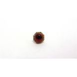 A CABOCHON GARNET RING stamped '9ct', enclosed by a seed pearl border, finger size F, 5.5g gross
