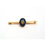 A FRENCH BAR BROOCH with control marks, set with an oval cut synthetic sapphire applied with a motif