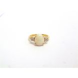 AN OPAL 9 CARAT GOLD RING with a trio of stones to each shoulder, finger size Q, 2.7g gross