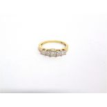 A 9 CARAT GOLD FIVE STONE PRINCESS CUT DIAMOND RING with a brilliant cut to each side of the head,