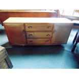 A LIGHT ERCOL SIDEBOARD fitted with three drawers flanked by cupboards, supported on four casters,