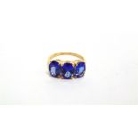 A 14 CARAT GOLD THREE STONE TANZANITE RING set with uniform oval cuts, finger size O 1/2, 2.9g
