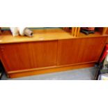 A TEAK SIDEBOARD with sliding doors, the left hand side with two sliding trays, 151cm wide 46cm deep