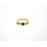 A SAPPHIRE AND DIAMOND RING unmarked, the round cut stone with a line of rose cuts to the shoulders,