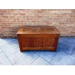A CONTINENTAL OAK COFFER WITH TRIPLE PANEL FRONT allover carved decoration, 108cm wide 52cm deep