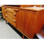 AN AUSTINSUITE TEAK SIDEBOARD fitted with three drawers flanked by cupboards