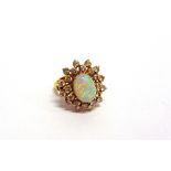 AN OPAL AND DIAMOND CLUSTER RING stamped '18KT', the oval cabochon enclosed by twenty four brilliant