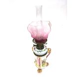 A CONTINENTAL OIL LAMP the cranberry coloured shade with acid etched decoration, the ceramic