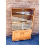 A LIGHT ERCOL STYLE GLAZED BOOKCASE with two adjustable shelves enclosed by sliding glass doors with