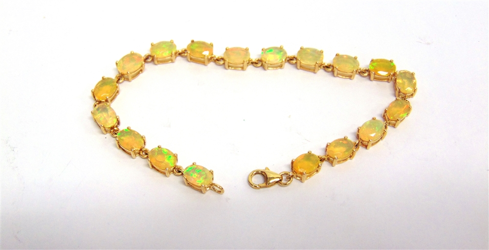 A 9 CARAT GOLD OPAL BRACELET composed of eighteen shallow oval cabochons, 18.5cm long, 7g gross