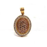 A 9 CARAT GOLD OVAL DIAMOND CLUSTER PENDANT with tinted diamonds to the centre, enclosed by a border